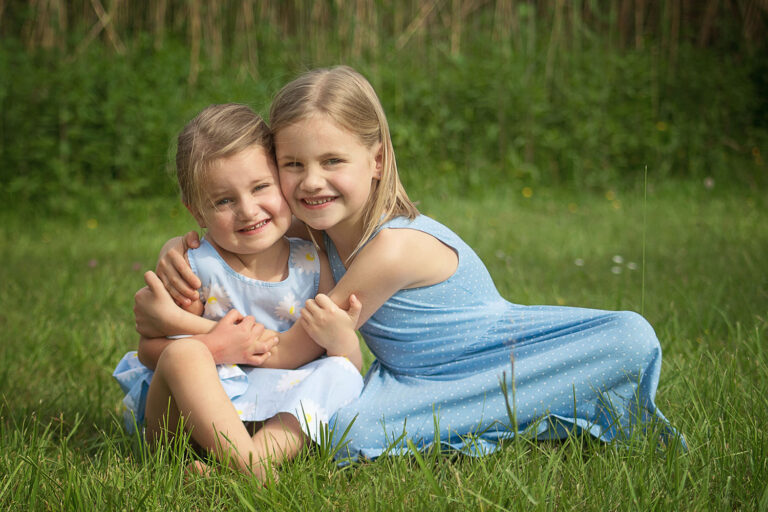 sibling sisters hugging sitting in a park in niagara falls